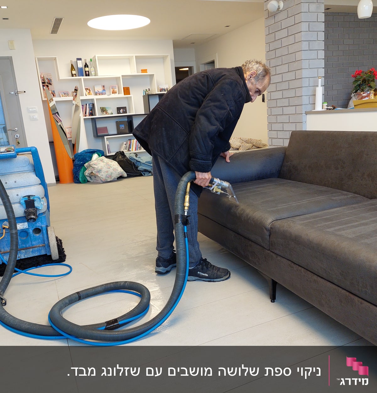 אדם מנקה ספה עם מכונת ניקוי מקצועית